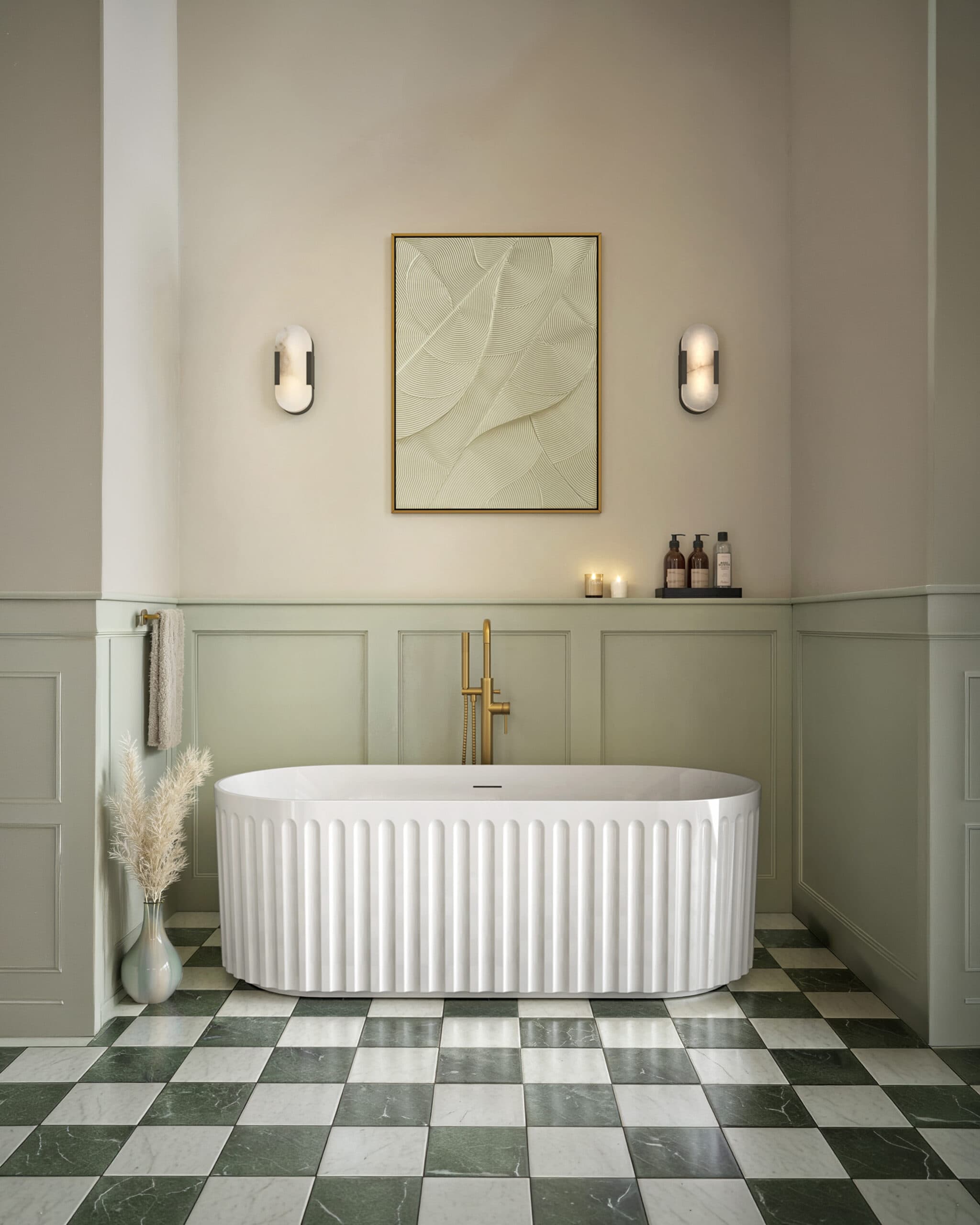 Fluted white freestanding bath, green wall panelling, checked floor and brass-coloured fittings.