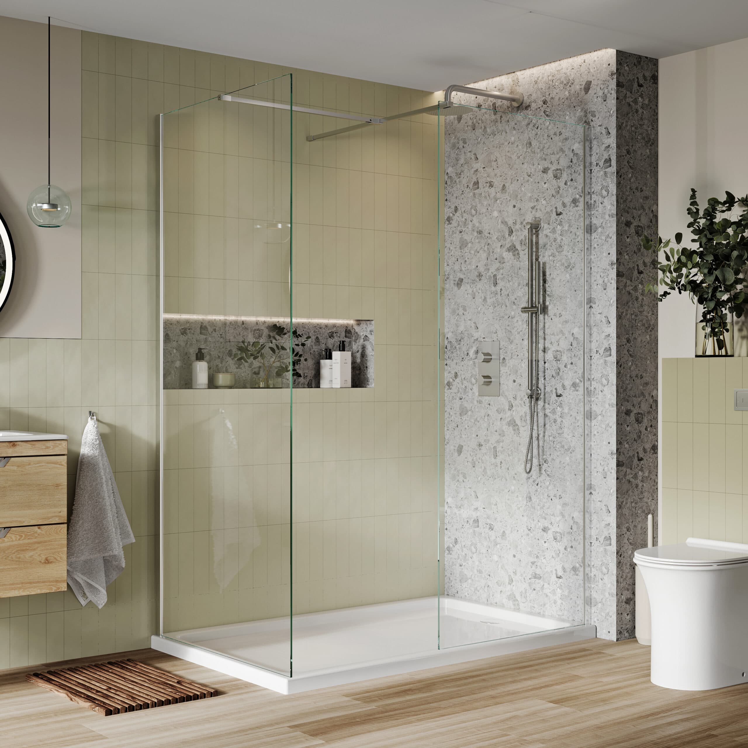 Clear shower screen and white tray beside pale green tiles and a speckled shower wall.