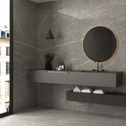 Dark veined wall and floor tiles surrounding a grey wall-mounted vanity and round mirror.
