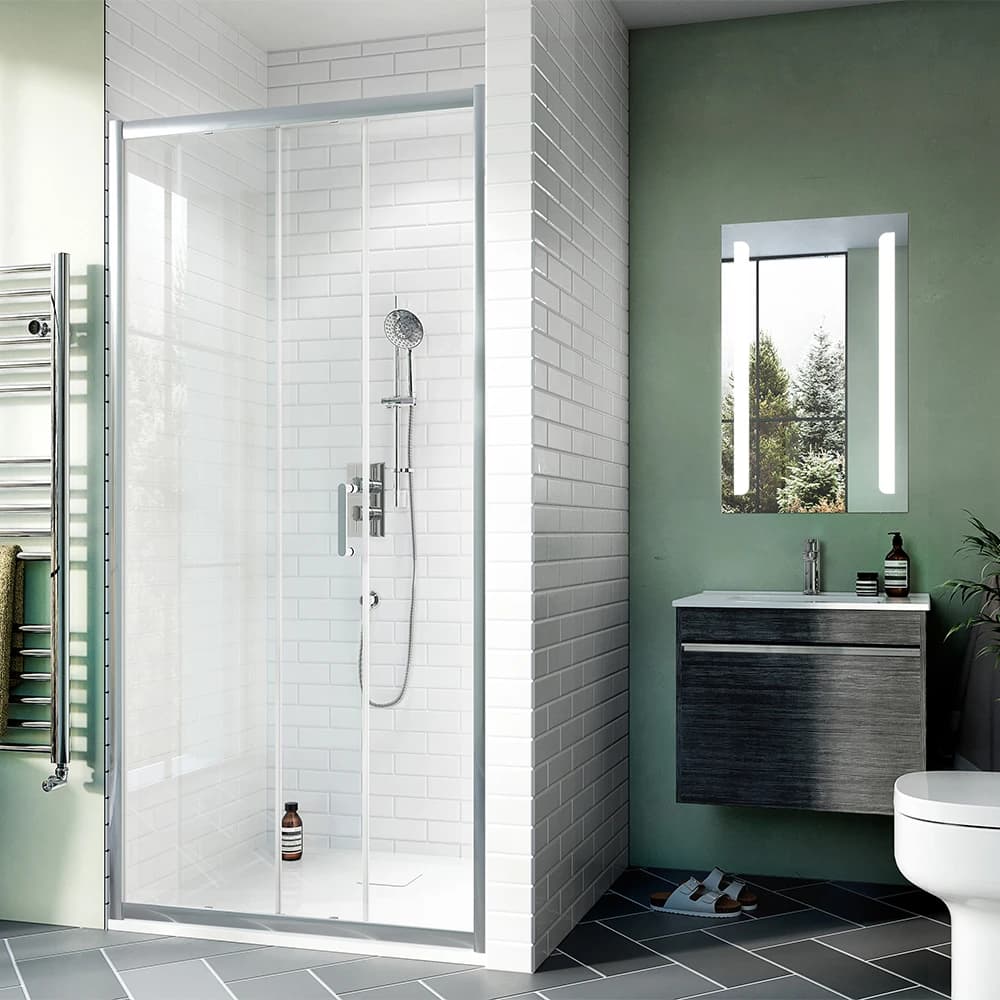 Sliding shower enclosure beside a dark wall-mounted vanity and illuminated mirror.
