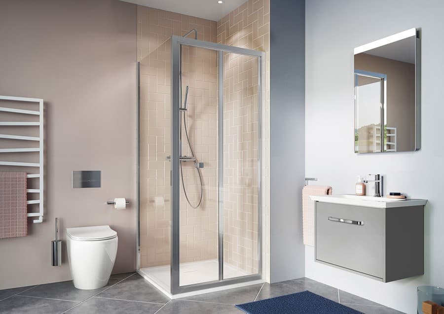 Chrome bifold corner shower between a toilet and grey vanity in a pink and grey room