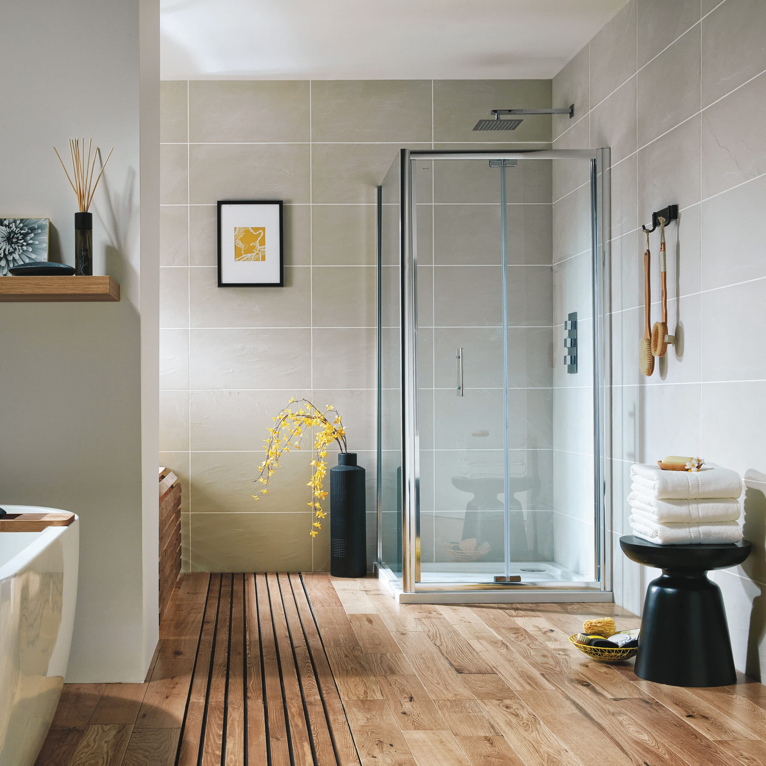 Chrome bifold shower door with beige wall panels, timber-effect floor and yellow flowers