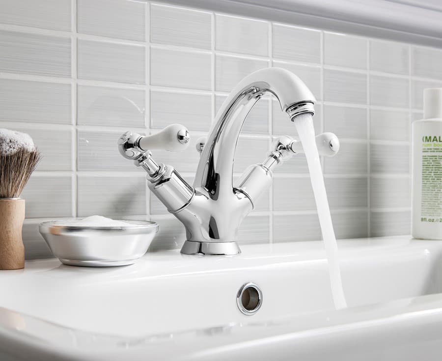 Chrome traditional basin mixer above a white basin with a visible overflow